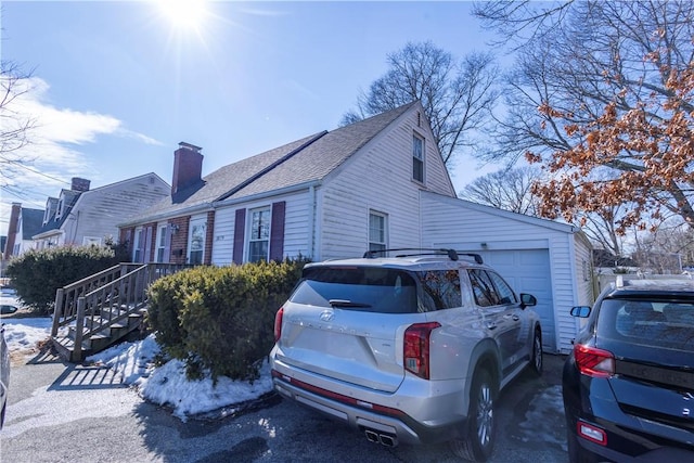 view of home's exterior featuring a shingled roof, stairway, a chimney, and a garage