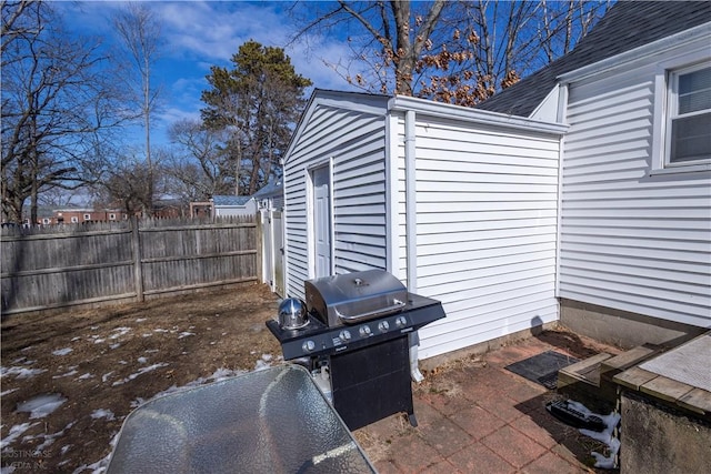 view of patio with an outdoor structure, a grill, and fence