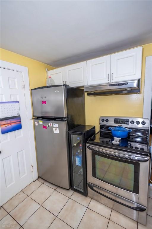 kitchen with beverage cooler, stainless steel appliances, white cabinetry, and under cabinet range hood