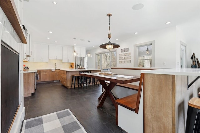 kitchen with a kitchen island, stainless steel appliances, light countertops, a kitchen bar, and backsplash