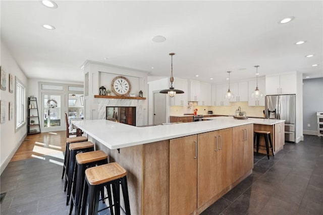 kitchen featuring a breakfast bar area, recessed lighting, light countertops, a large island, and stainless steel fridge