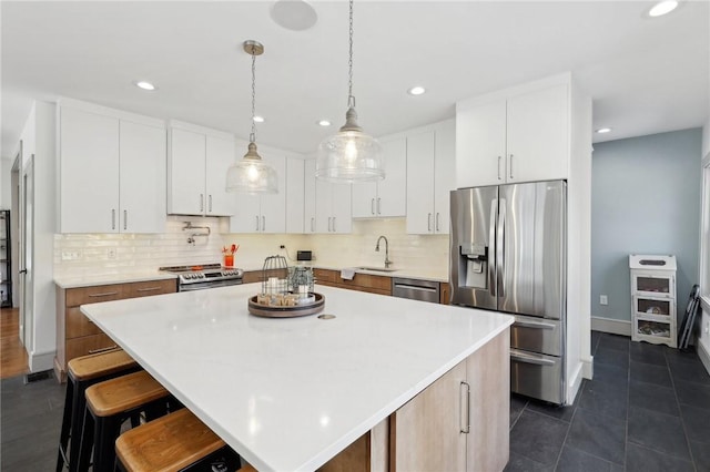 kitchen featuring light countertops, appliances with stainless steel finishes, a breakfast bar area, and tasteful backsplash