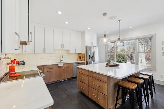 kitchen with decorative backsplash, a breakfast bar area, appliances with stainless steel finishes, light countertops, and a sink