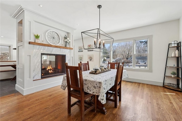 dining area featuring a fireplace, baseboards, wood finished floors, and recessed lighting