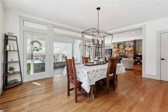 dining room with light wood-style floors, a fireplace, and an inviting chandelier