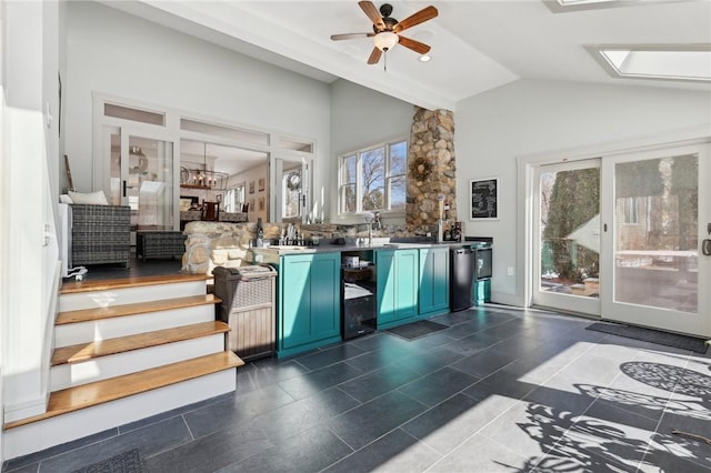 kitchen featuring a skylight, high vaulted ceiling, a ceiling fan, blue cabinets, and dishwasher