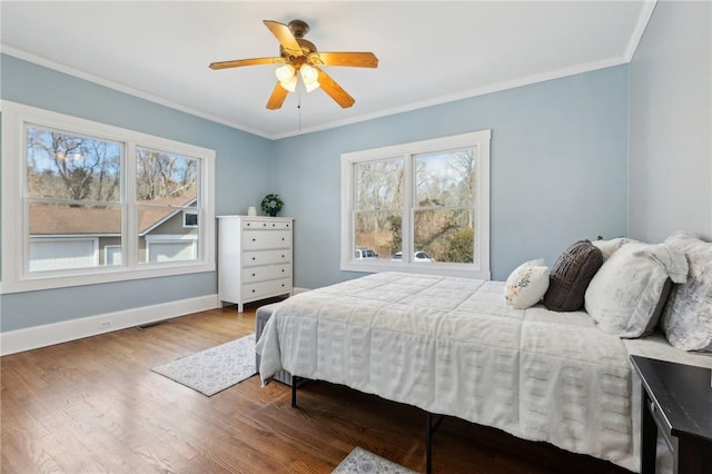 bedroom featuring baseboards, visible vents, ornamental molding, and wood finished floors