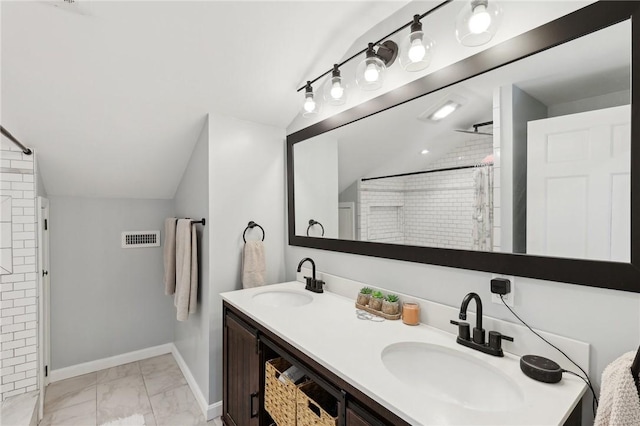 full bathroom featuring a tile shower, visible vents, vaulted ceiling, and a sink