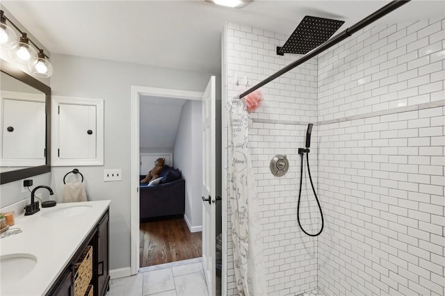 full bathroom with ensuite bathroom, a sink, baseboards, a tile shower, and double vanity