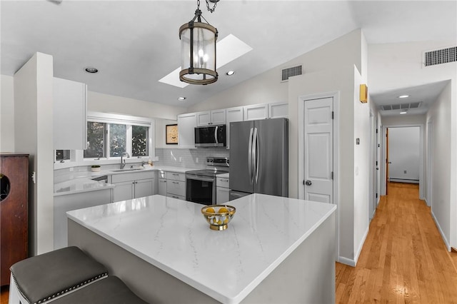 kitchen featuring lofted ceiling, appliances with stainless steel finishes, a sink, and visible vents