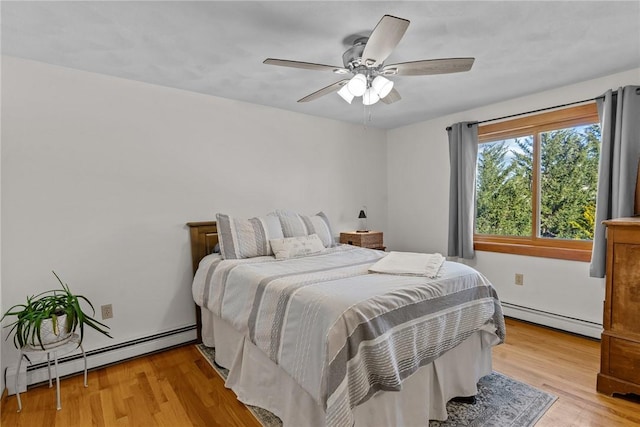 bedroom featuring ceiling fan, baseboard heating, and wood finished floors