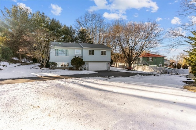 view of front of property featuring an attached garage, driveway, and fence