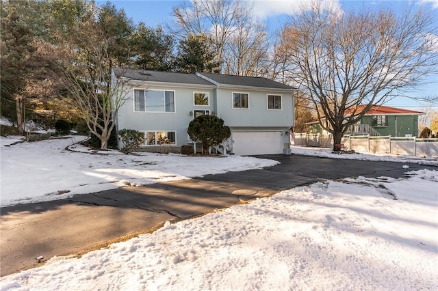 split foyer home featuring a garage, driveway, and fence