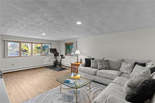 living room featuring a baseboard radiator, a healthy amount of sunlight, baseboards, and wood finished floors