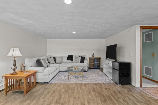 living area featuring recessed lighting, visible vents, baseboards, and wood finished floors