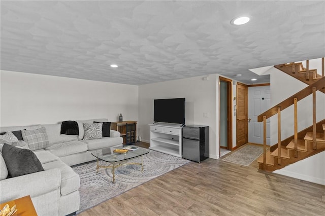 living area featuring baseboards, stairway, wood finished floors, a textured ceiling, and recessed lighting