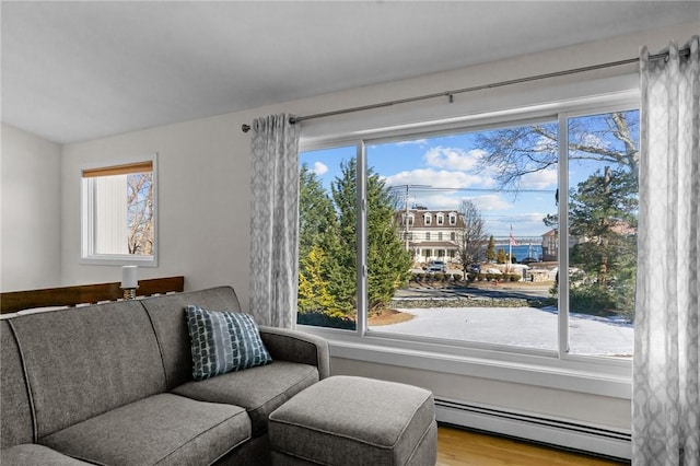 living area featuring a baseboard heating unit, wood finished floors, and a healthy amount of sunlight