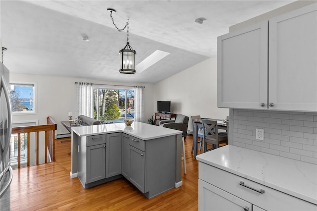 kitchen with gray cabinets, plenty of natural light, light wood-style flooring, and open floor plan