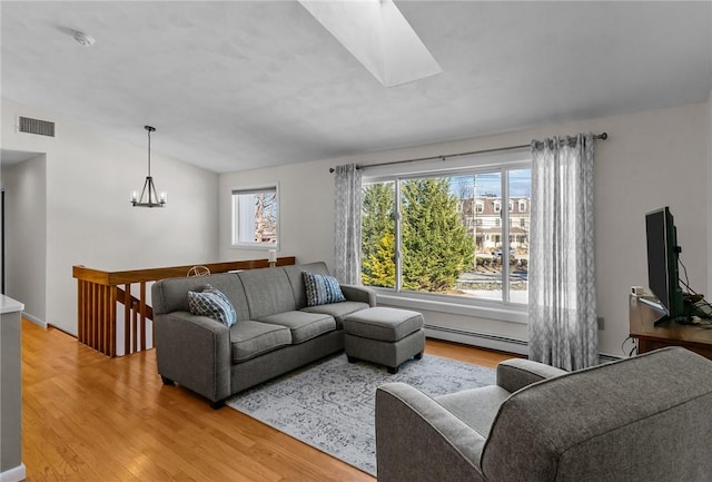 living room featuring visible vents, lofted ceiling with skylight, a baseboard radiator, an inviting chandelier, and light wood-style floors