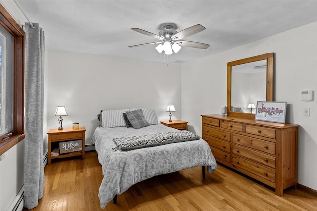 bedroom featuring baseboard heating, wood finished floors, and a ceiling fan