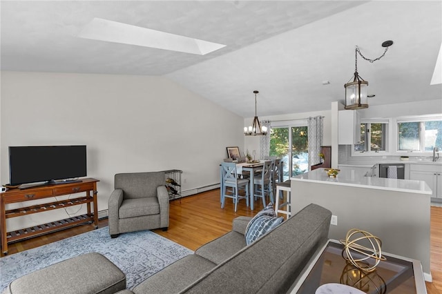 living area with lofted ceiling with skylight, a baseboard radiator, an inviting chandelier, and wood finished floors