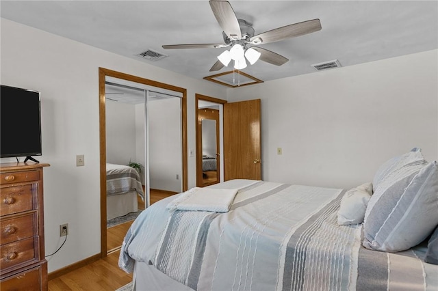 bedroom with light wood-style floors, a ceiling fan, visible vents, and a closet