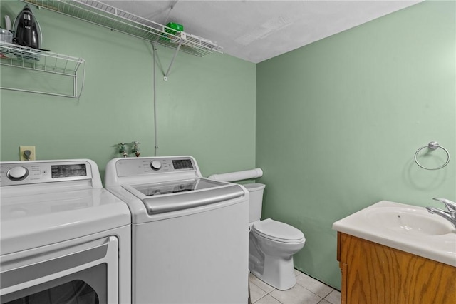 clothes washing area with laundry area, independent washer and dryer, a sink, and light tile patterned floors