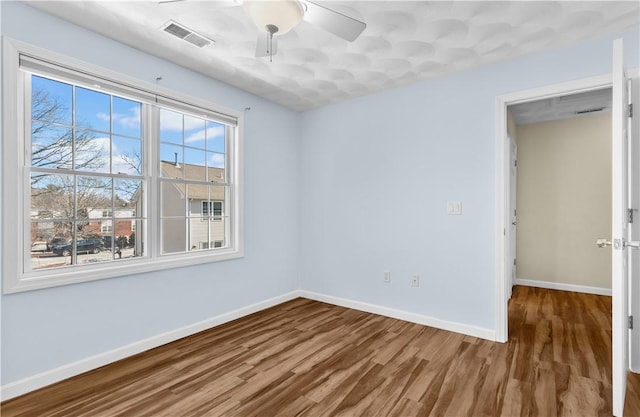 unfurnished room featuring baseboards, visible vents, ceiling fan, and wood finished floors