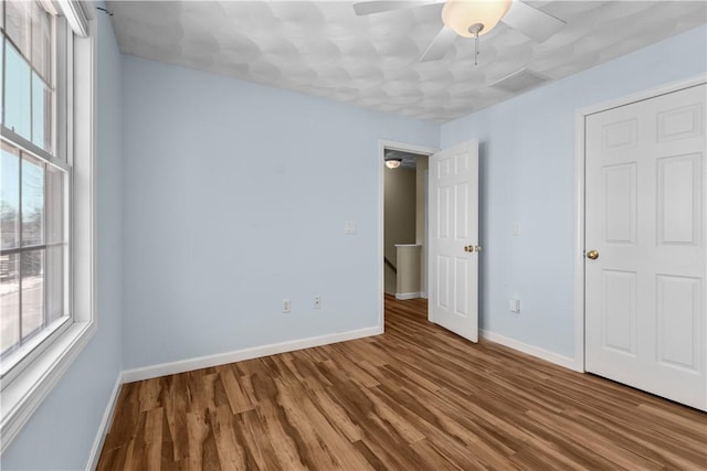 unfurnished bedroom featuring visible vents, baseboards, ceiling fan, and wood finished floors