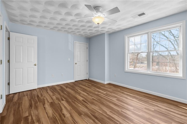 unfurnished bedroom with a ceiling fan, baseboards, visible vents, and wood finished floors