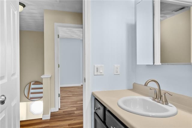 bathroom with baseboards, visible vents, wood finished floors, and vanity