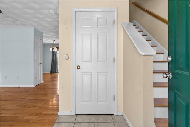 foyer entrance featuring light wood finished floors, baseboards, and stairway