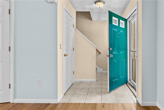 entryway featuring light tile patterned flooring, baseboards, and stairs