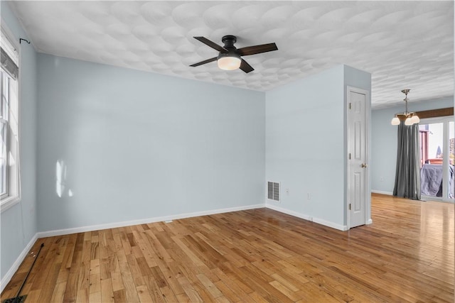 unfurnished room with light wood finished floors, visible vents, and baseboards