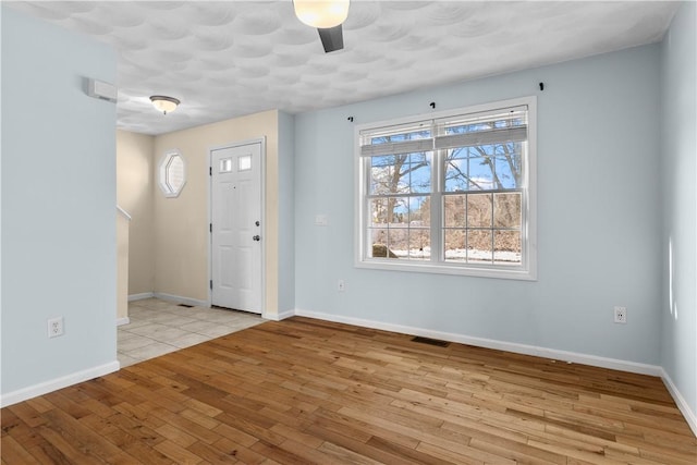 foyer with light wood finished floors, visible vents, and baseboards