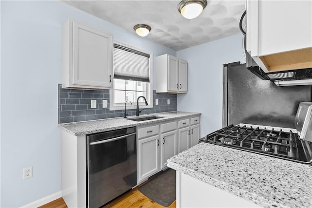 kitchen featuring a sink, white cabinets, appliances with stainless steel finishes, backsplash, and light stone countertops