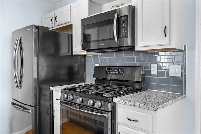 kitchen featuring light stone counters, white cabinetry, stainless steel appliances, and decorative backsplash