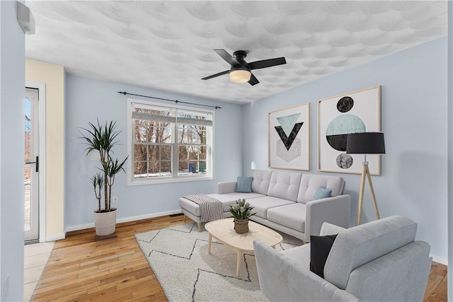 living room with light wood finished floors, ceiling fan, and baseboards