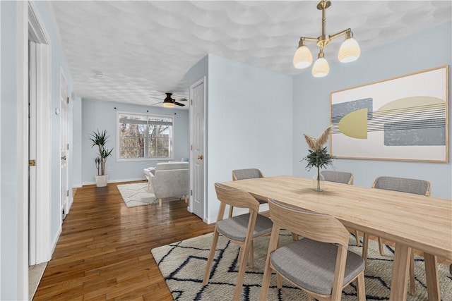 dining area with a notable chandelier, dark wood finished floors, and baseboards