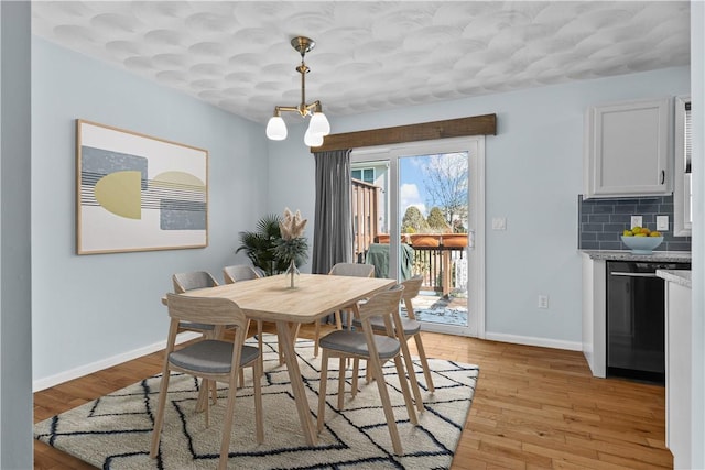 dining space with baseboards, a notable chandelier, and light wood finished floors