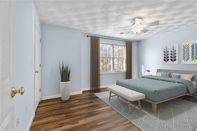 bedroom with visible vents, dark wood-type flooring, a ceiling fan, and baseboards