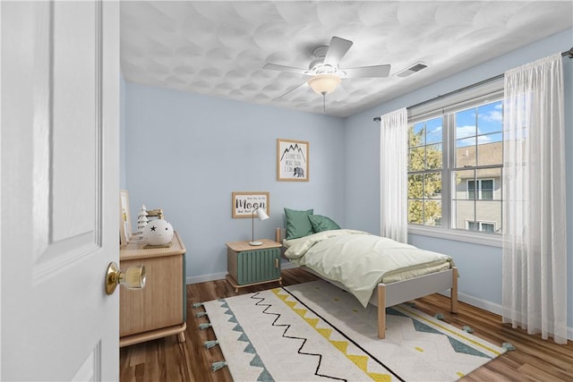 bedroom featuring visible vents, ceiling fan, baseboards, and wood finished floors