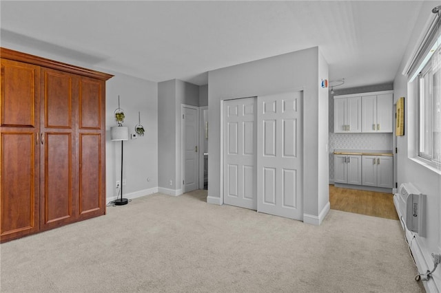 unfurnished bedroom with light carpet, a wall unit AC, baseboards, and a closet