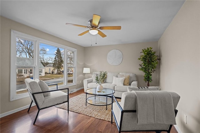 living room featuring visible vents, baseboards, dark wood finished floors, and a ceiling fan