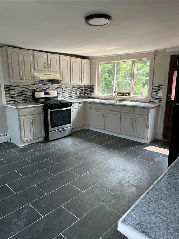 kitchen with white cabinets, light countertops, decorative backsplash, and gas stove