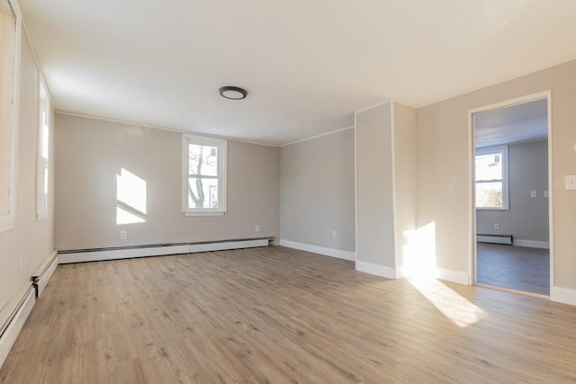 spare room featuring baseboard heating, plenty of natural light, and light wood-style flooring