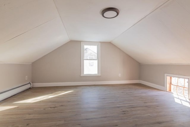 additional living space with lofted ceiling, plenty of natural light, baseboard heating, and wood finished floors