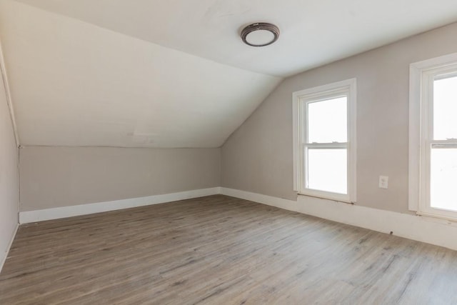 bonus room with lofted ceiling, plenty of natural light, and wood finished floors