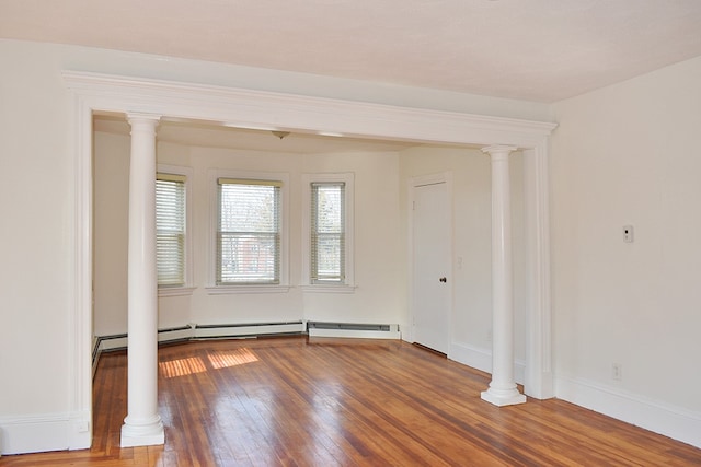 empty room featuring baseboards, ornate columns, and hardwood / wood-style flooring