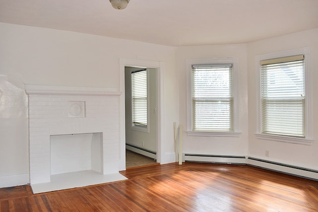 unfurnished living room with a brick fireplace, a baseboard heating unit, and wood finished floors